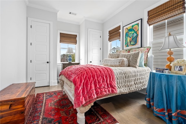 bedroom with multiple windows, crown molding, and wood-type flooring