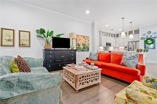 living room with hardwood / wood-style floors, crown molding, and sink