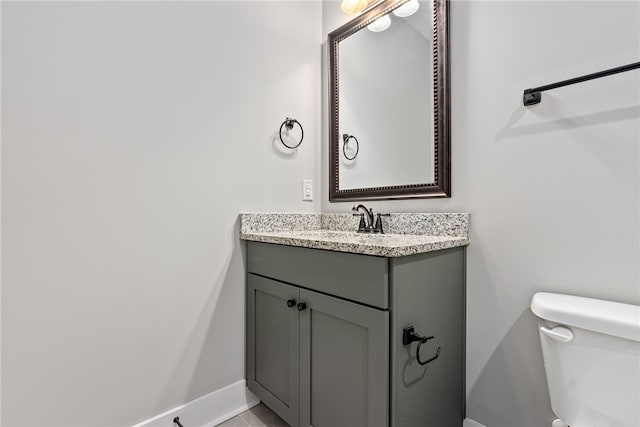 bathroom with baseboards, toilet, and vanity