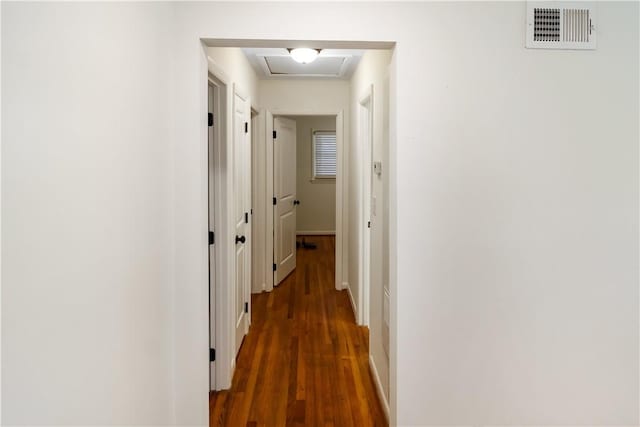 corridor featuring wood finished floors, attic access, baseboards, and visible vents