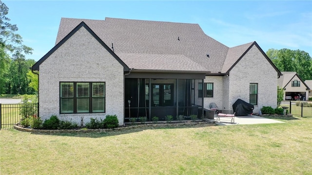 back of property with a lawn, a patio area, and a sunroom