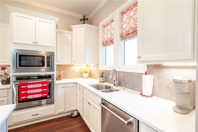 kitchen featuring appliances with stainless steel finishes, tasteful backsplash, crown molding, sink, and white cabinetry