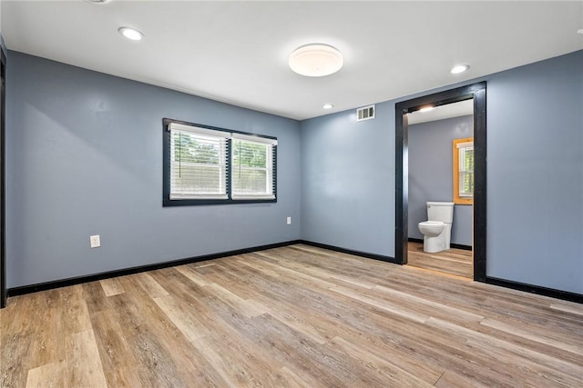 unfurnished bedroom featuring wood finished floors, ensuite bath, recessed lighting, and baseboards