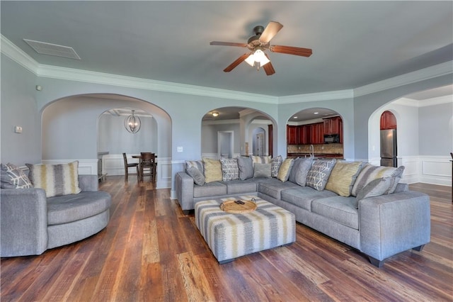 151 Landing Way, Smiths Station, AL 36877 - living area with arched walkways, a ceiling fan, crown molding, a wainscoted wall, and dark wood finished floors