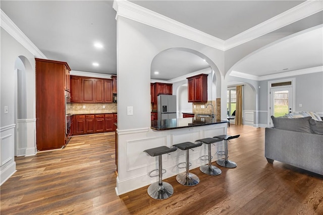 151 Landing Way, Smiths Station, AL 36877 - kitchen with stainless steel fridge with ice dispenser, reddish brown cabinets, arched walkways, open floor plan, and crown molding