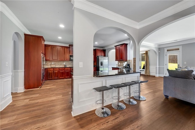 151 Landing Way, Smiths Station, AL 36877 - kitchen with stainless steel appliances, reddish brown cabinets, open floor plan, arched walkways, and ornamental molding