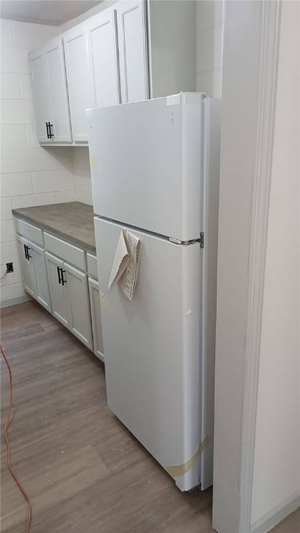 314 E Rosa Park, Tuskegee, AL 36083 - kitchen with freestanding refrigerator, light wood finished floors, white cabinets, and dark countertops