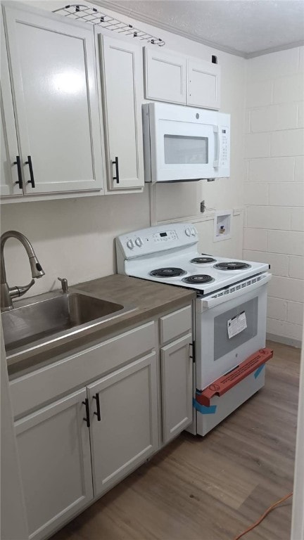 314 E Rosa Park, Tuskegee, AL 36083 - kitchen with white appliances, concrete block wall, wood finished floors, and white cabinetry
