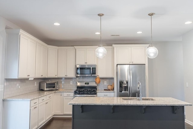 kitchen with appliances with stainless steel finishes, sink, pendant lighting, and light stone counters