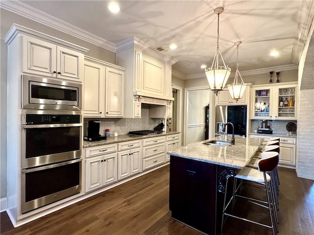 kitchen featuring stainless steel appliances, light stone countertops, a sink, and decorative backsplash
