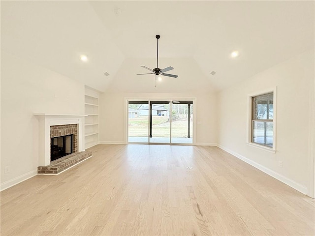 unfurnished living room featuring vaulted ceiling, a brick fireplace, built in shelves, ceiling fan, and light hardwood / wood-style floors