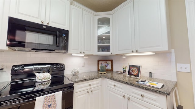 kitchen featuring backsplash, white cabinetry, black appliances, and dark stone countertops