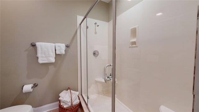 bathroom featuring a shower with shower door and toilet