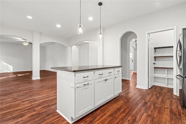 kitchen with arched walkways, freestanding refrigerator, a ceiling fan, and dark wood-style flooring