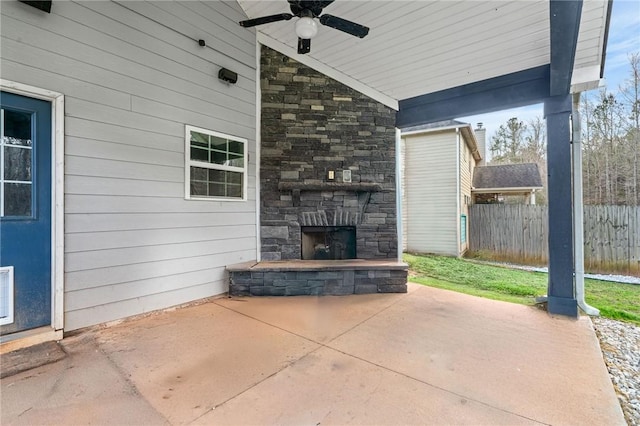 view of patio featuring an outdoor stone fireplace, ceiling fan, and fence