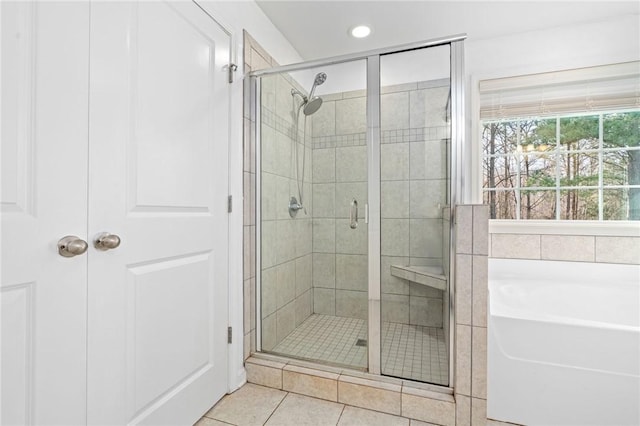 bathroom featuring tile patterned floors, a bath, and a stall shower