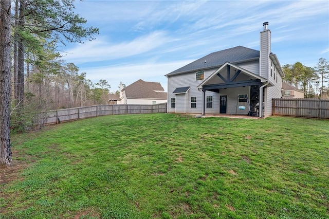 back of house featuring a patio area, a fenced backyard, a chimney, and a yard