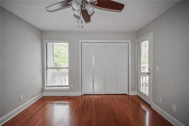 unfurnished bedroom with wood finished floors, baseboards, a closet, and ceiling fan