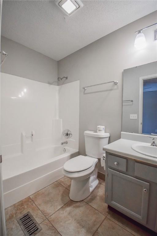 bathroom with a textured ceiling, toilet, shower / bath combination, vanity, and tile patterned flooring