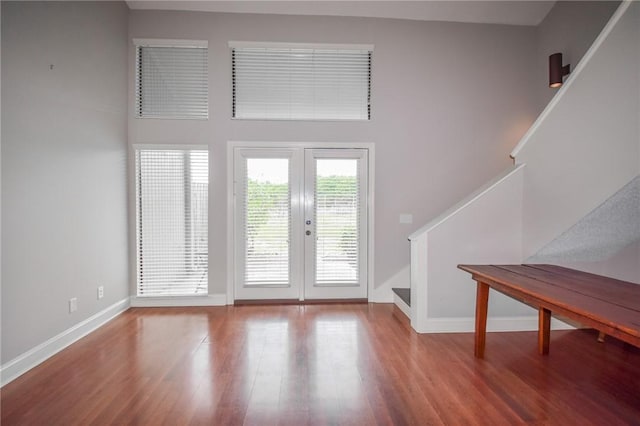 unfurnished living room featuring stairway, french doors, wood finished floors, and baseboards