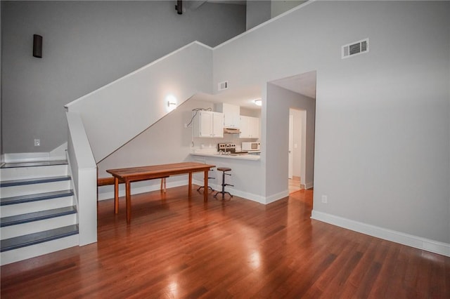 living room with stairway, a towering ceiling, dark wood finished floors, and baseboards