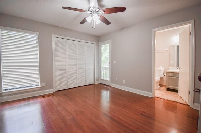 unfurnished bedroom with wood finished floors, baseboards, a ceiling fan, and ensuite bathroom