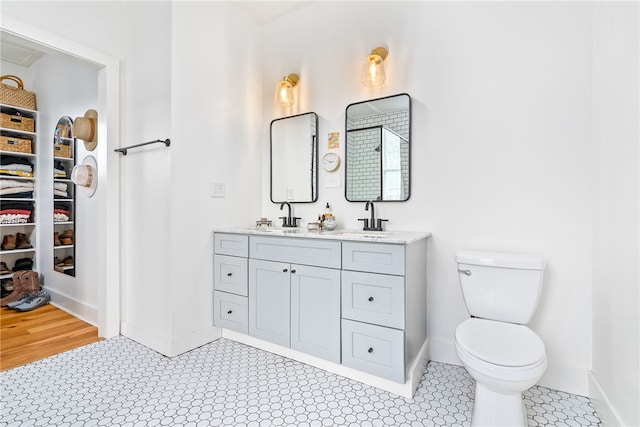 full bathroom with baseboards, a sink, toilet, and double vanity