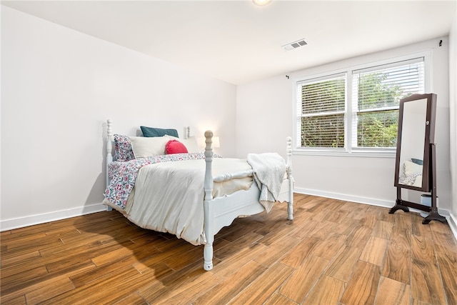 bedroom with wood finished floors, visible vents, and baseboards