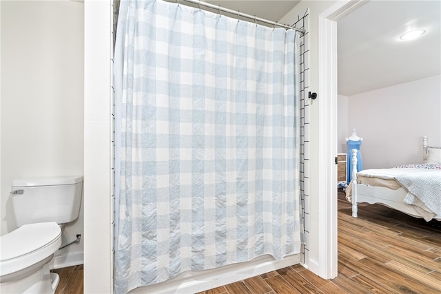 ensuite bathroom with toilet, curtained shower, ensuite bath, and wood finished floors