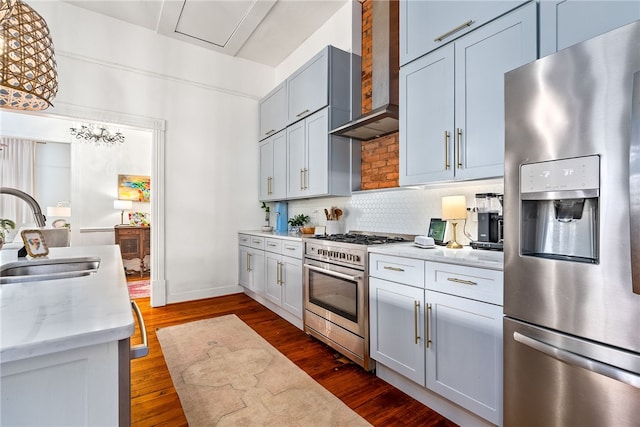 kitchen with decorative backsplash, appliances with stainless steel finishes, dark wood-type flooring, a sink, and wall chimney range hood