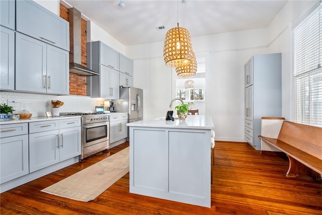 kitchen featuring decorative backsplash, dark wood finished floors, wall chimney exhaust hood, appliances with stainless steel finishes, and light countertops