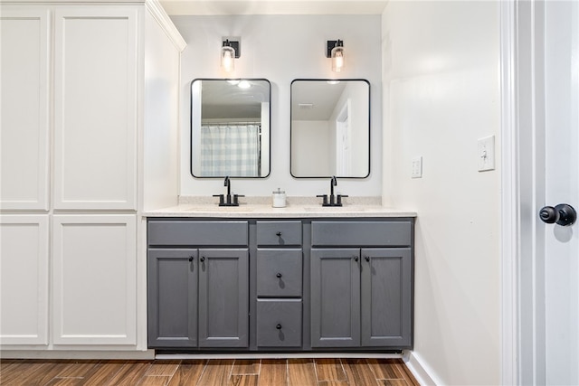 full bathroom with wood tiled floor, a sink, baseboards, and double vanity