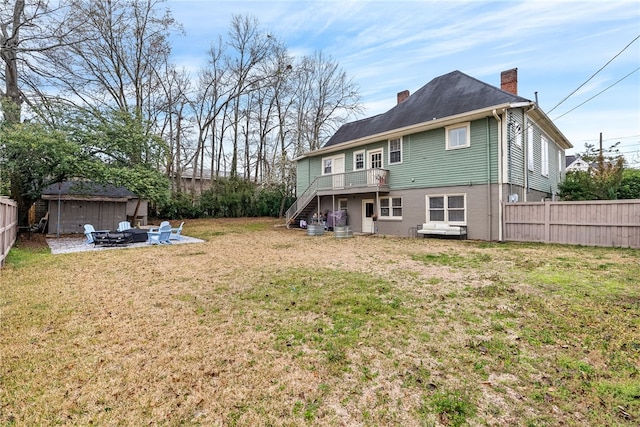 rear view of house featuring a fire pit, a fenced backyard, a chimney, stairs, and a yard