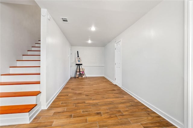 interior space with stairway, wood finished floors, visible vents, and baseboards