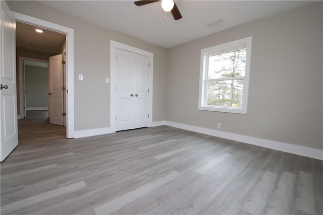 unfurnished bedroom featuring ceiling fan, light wood-type flooring, and a closet