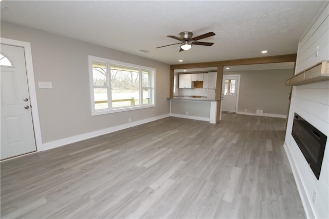 unfurnished living room featuring ceiling fan, light wood-type flooring, and a fireplace