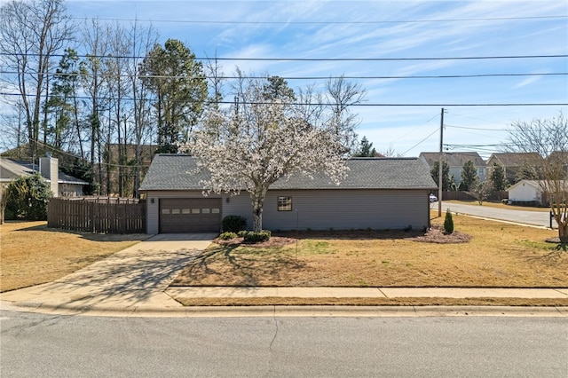 view of front of house with driveway, a garage, fence, and roof with shingles