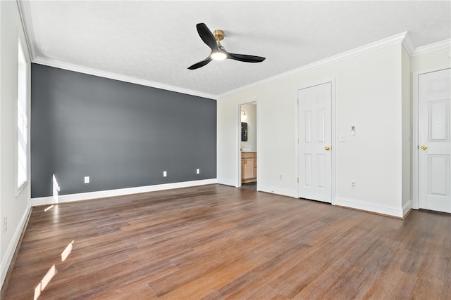 unfurnished bedroom with baseboards, wood finished floors, connected bathroom, and crown molding