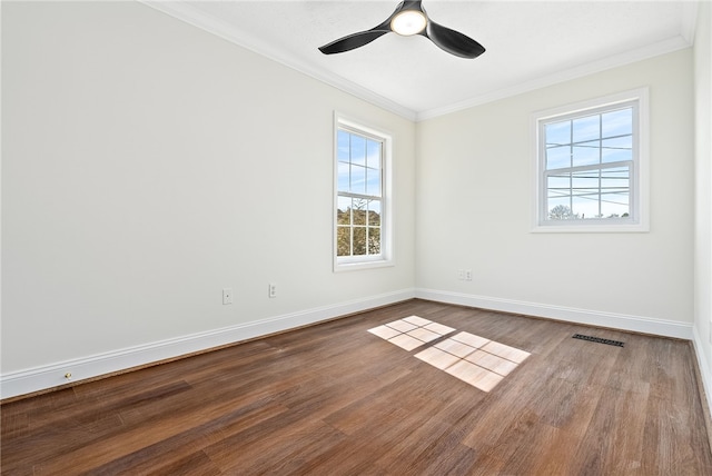 empty room with ornamental molding, dark wood-type flooring, baseboards, and a ceiling fan