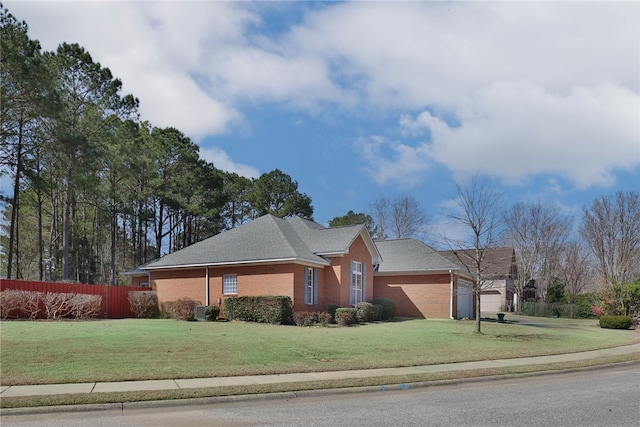 single story home featuring a front lawn, fence, concrete driveway, an attached garage, and brick siding