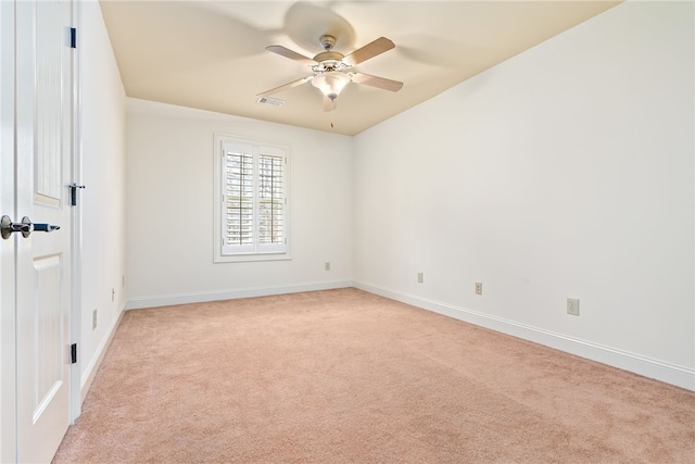 spare room with visible vents, baseboards, light colored carpet, and a ceiling fan