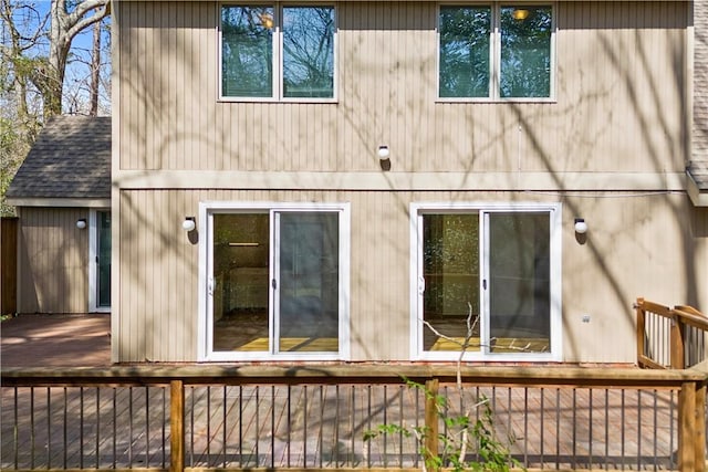 back of property featuring fence, a deck, and roof with shingles