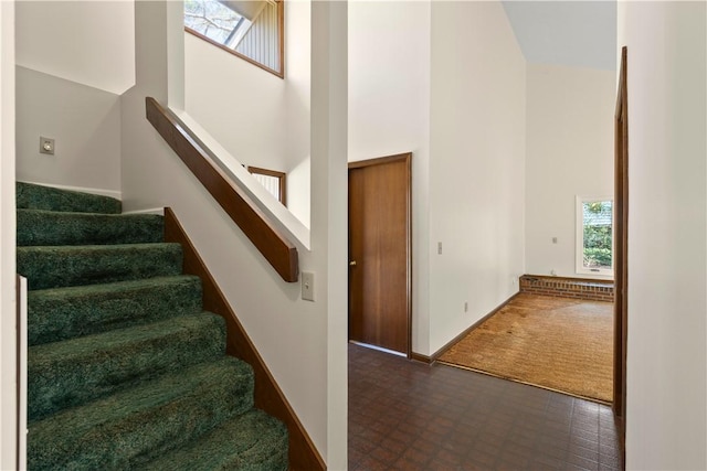 staircase featuring a high ceiling and baseboards