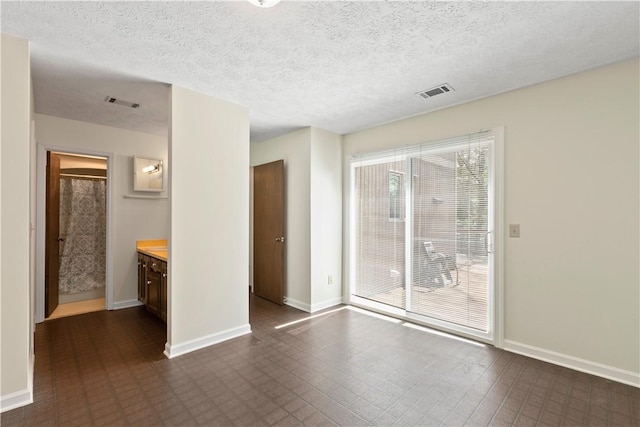 empty room featuring visible vents, a textured ceiling, and baseboards