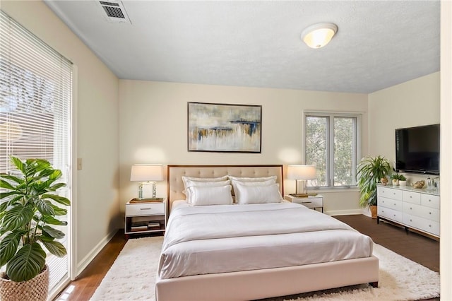 bedroom with dark wood finished floors, visible vents, and baseboards