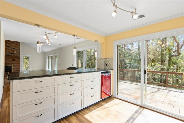 kitchen featuring visible vents, white cabinets, backsplash, dark stone counters, and light wood finished floors