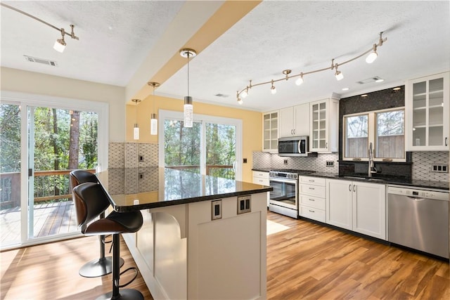 kitchen with visible vents, a breakfast bar, stainless steel appliances, light wood-type flooring, and a sink