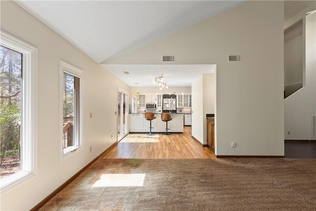 unfurnished living room featuring lofted ceiling, visible vents, and light carpet