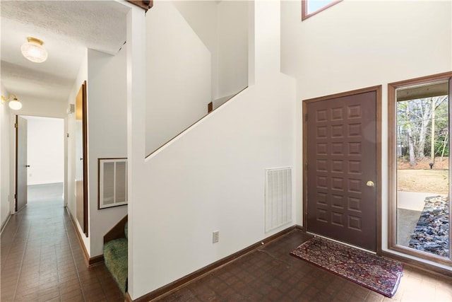 foyer entrance featuring a towering ceiling, baseboards, stairs, and visible vents