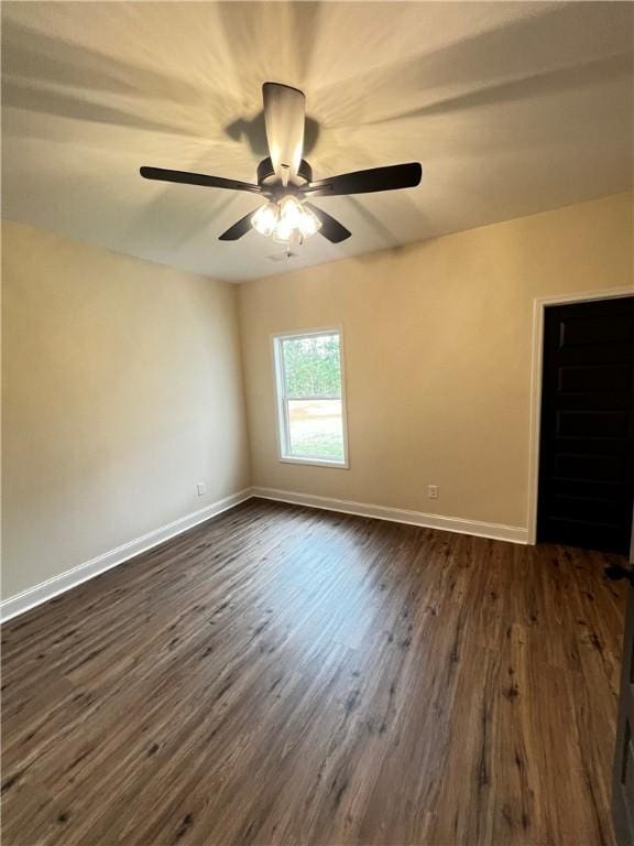empty room featuring baseboards, a ceiling fan, and dark wood finished floors